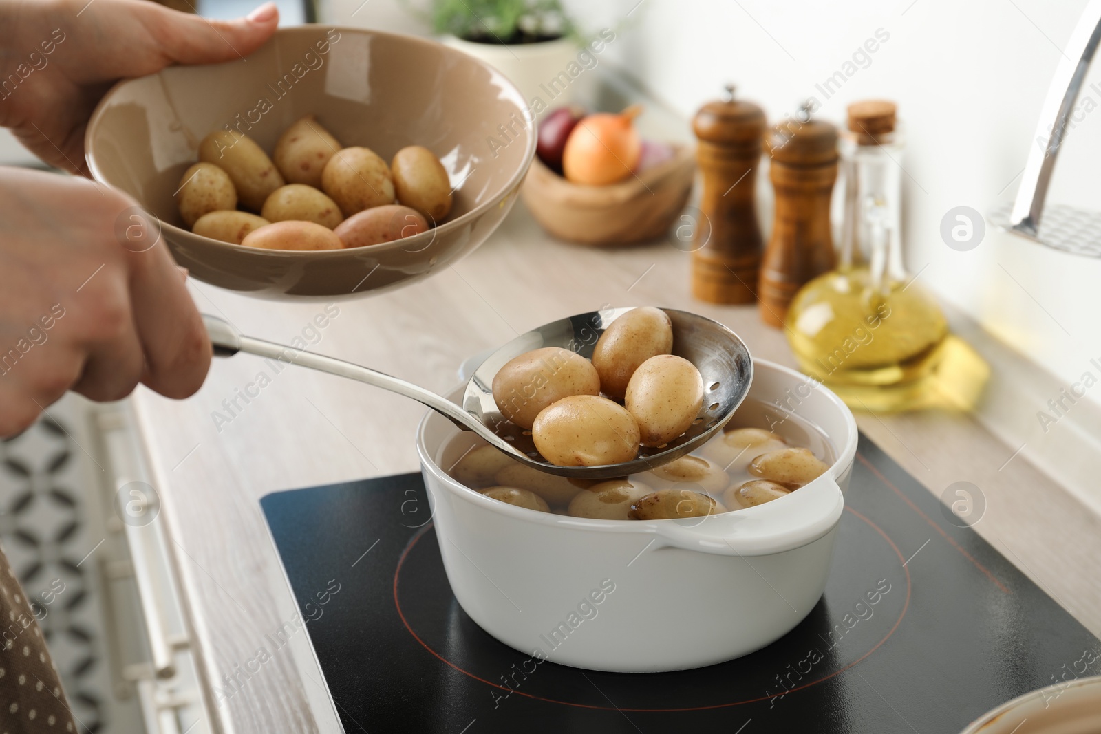 Photo of Woman taking potatoes from pot on stove, closeup