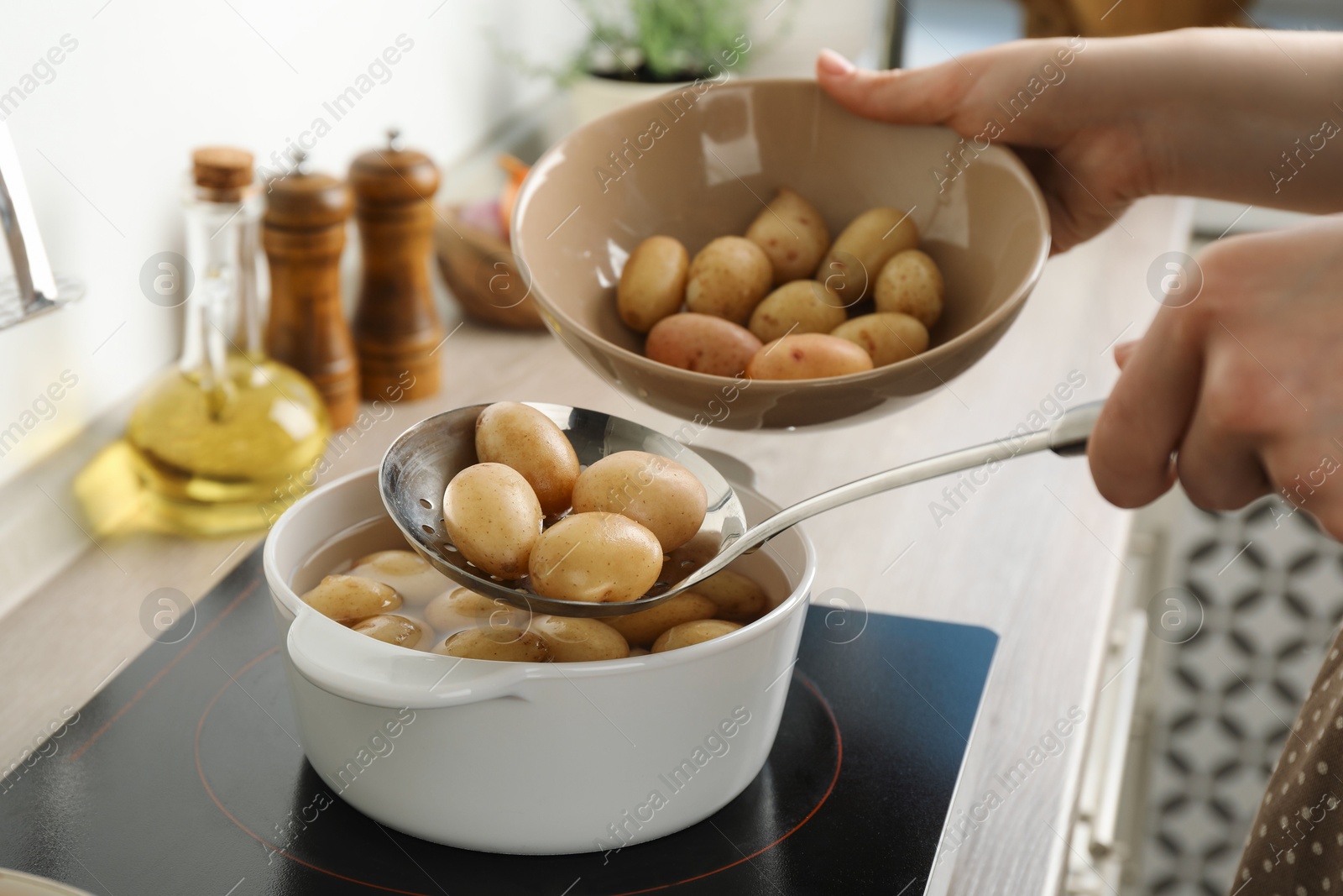 Photo of Woman taking potatoes from pot on stove, closeup