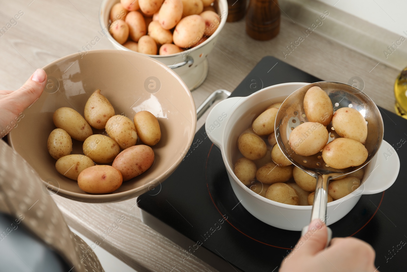 Photo of Woman taking potatoes from pot on stove, closeup