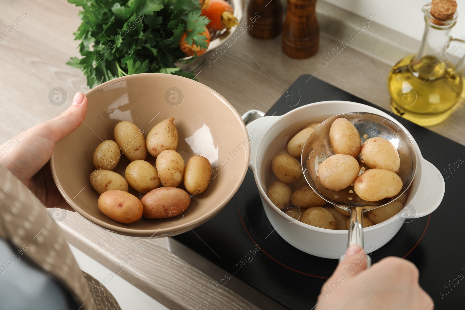 Photo of Woman taking potatoes from pot on stove, closeup