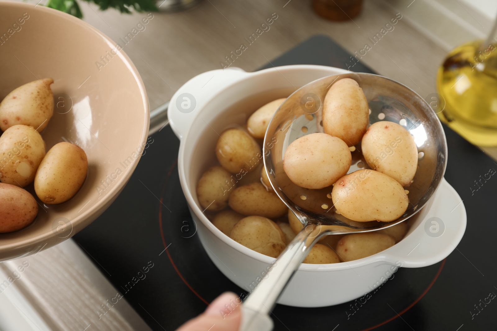 Photo of Woman taking potatoes from pot on stove, closeup