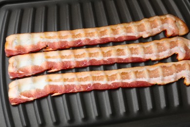 Photo of Raw slices of bacon on grill, closeup