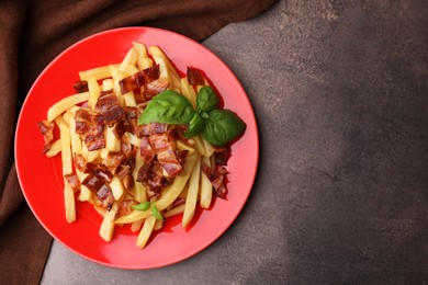 Photo of Delicious French fries with bacon and basil on brown background, top view. Space for text