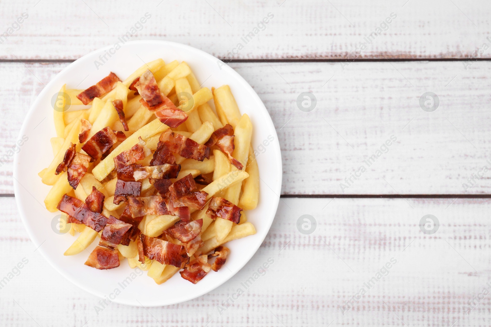 Photo of Delicious French fries with bacon on wooden rustic table, top view. Space for text