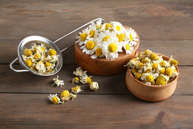 Photo of Dry and fresh chamomile flowers on wooden table