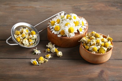 Dry and fresh chamomile flowers on wooden table