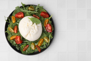 Photo of Delicious burrata salad on white tiled table, top view. Space for text