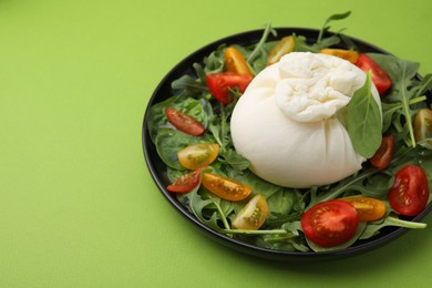 Photo of Delicious burrata salad on green table, closeup. Space for text