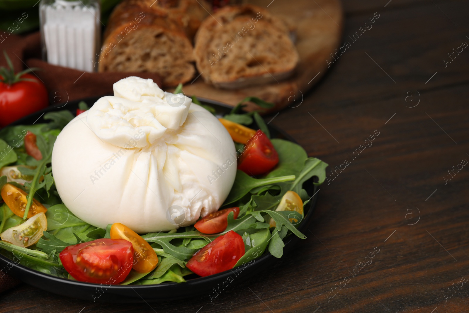 Photo of Delicious burrata salad on wooden table, closeup. Space for text