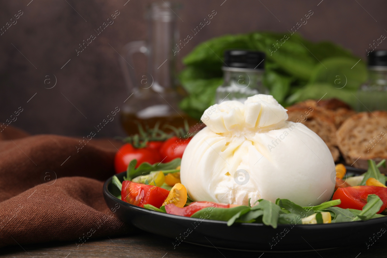 Photo of Delicious burrata salad on wooden table, closeup