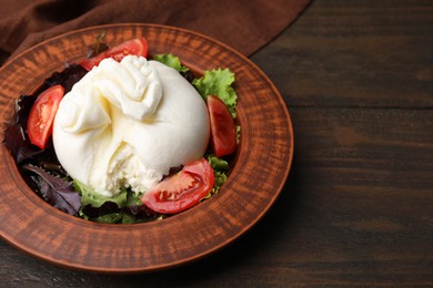 Photo of Delicious burrata salad in bowl on wooden table, closeup. Space for text