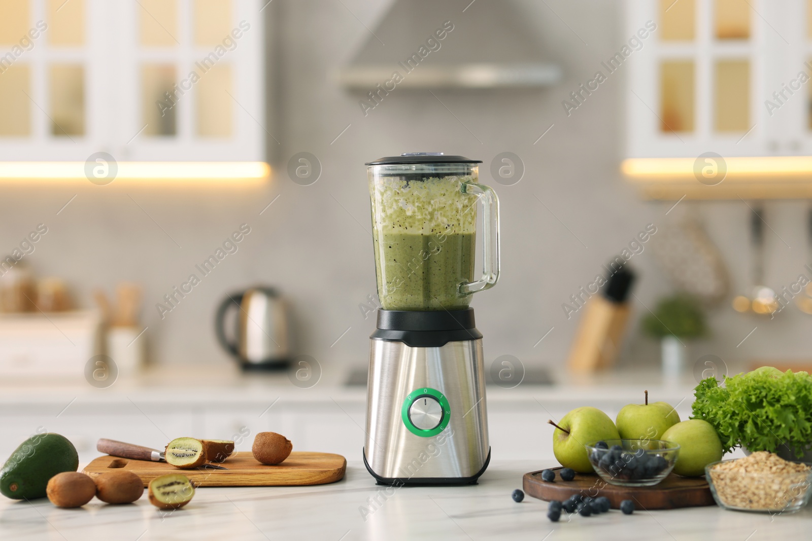 Photo of Modern blender with smoothie and ingredients at white marble table in kitchen