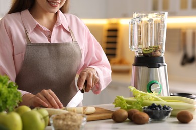 Woman making delicious smoothie with blender at white marble table in kitchen, closeup