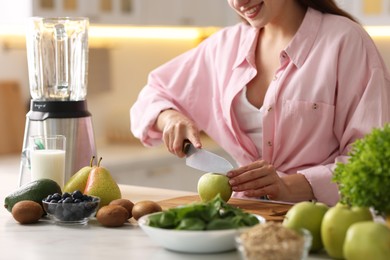 Photo of Woman making delicious smoothie with blender at white marble table in kitchen, closeup