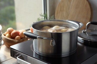 Photo of Boiling potatoes in pot on stove in kitchen