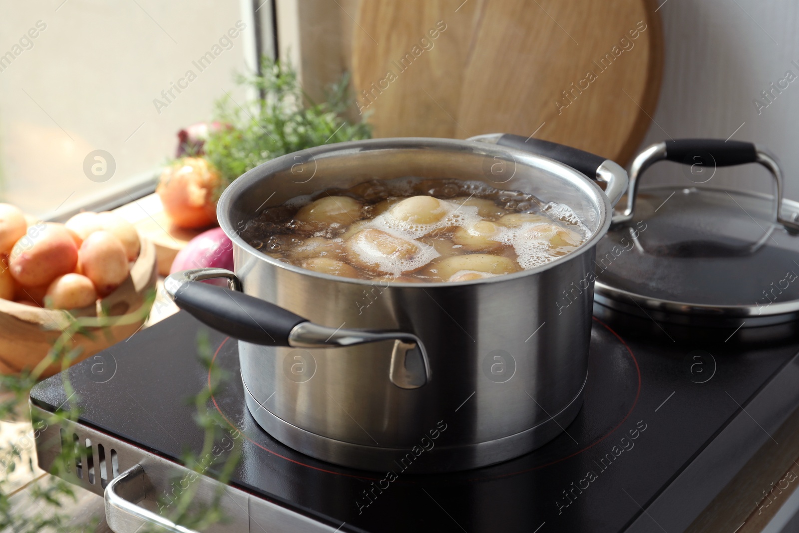 Photo of Boiling potatoes in pot on stove in kitchen