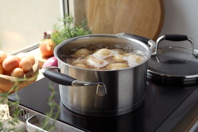 Photo of Boiling potatoes in pot on stove in kitchen