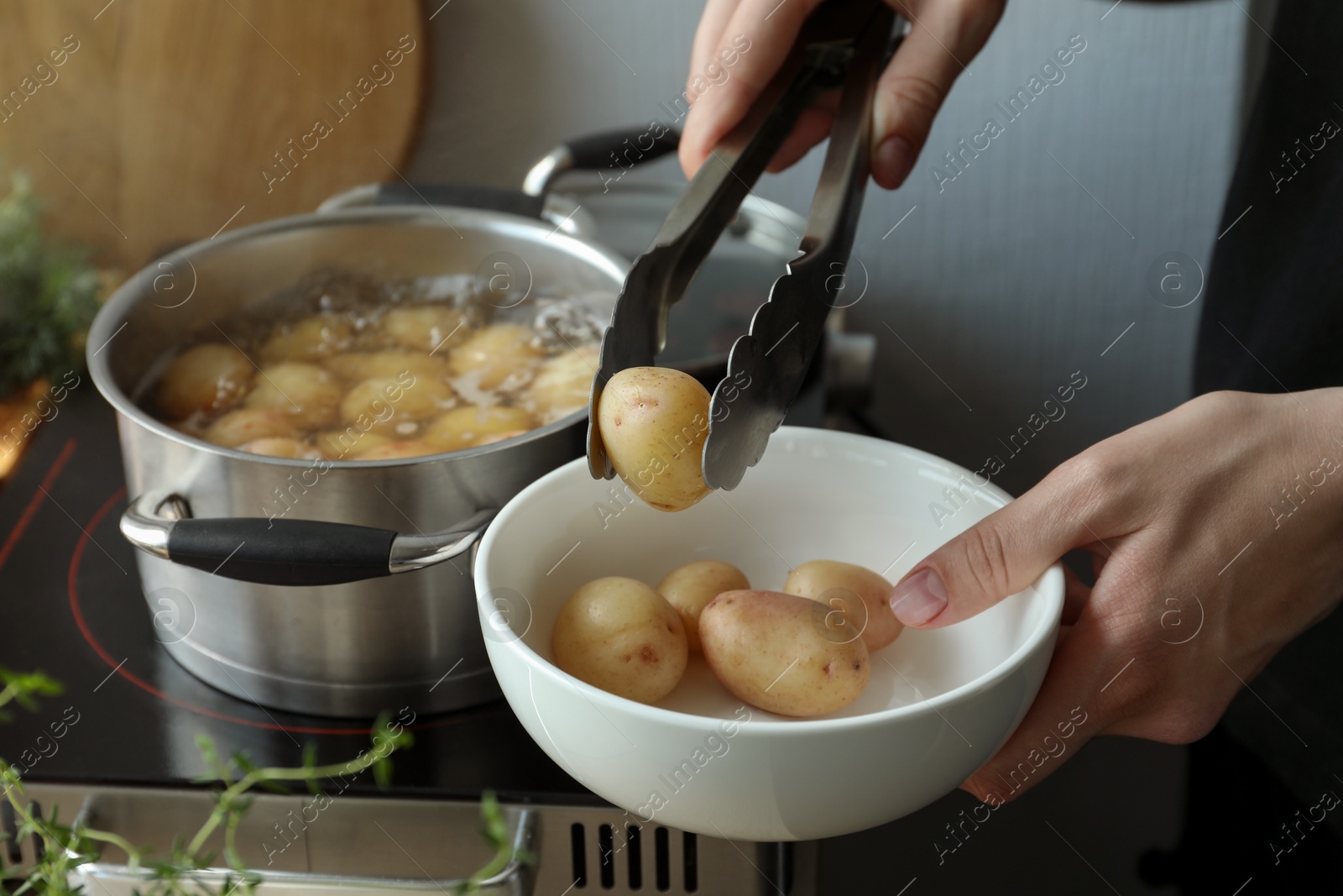 Photo of Woman taking potato from bowl at table, closeup