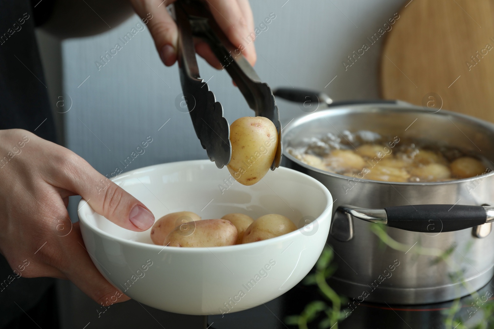 Photo of Woman taking potato from bowl at table, closeup