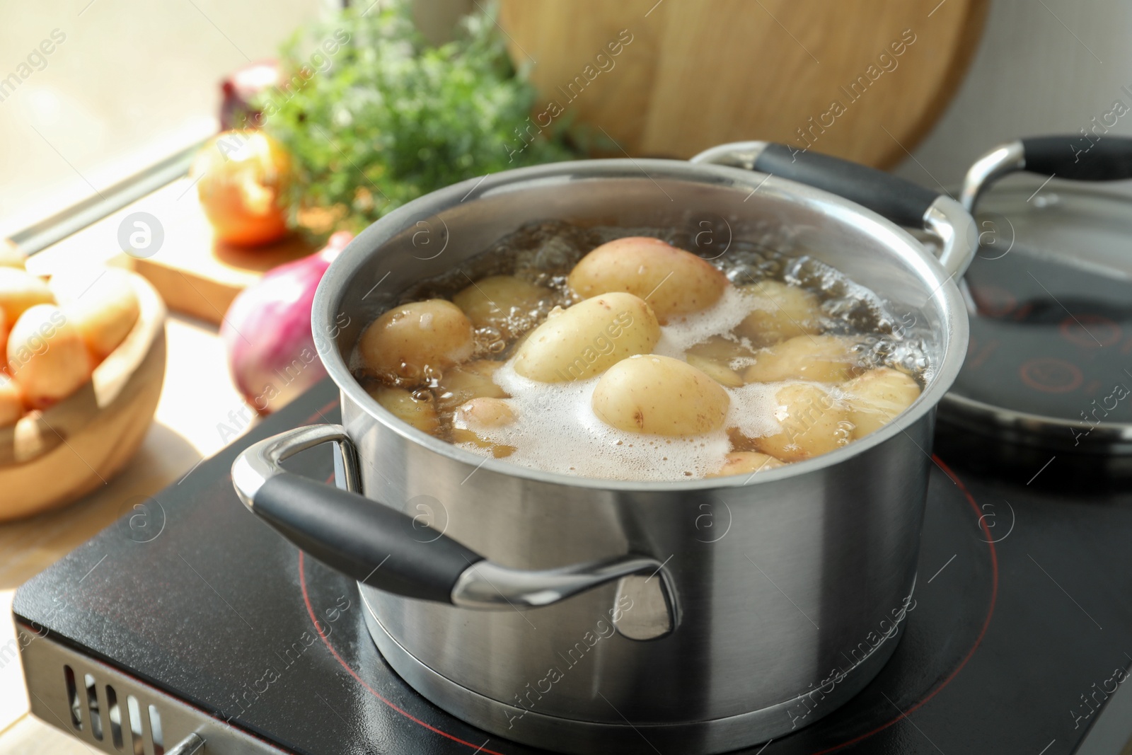 Photo of Boiling potatoes in pot on stove in kitchen