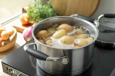 Photo of Boiling potatoes in pot on stove in kitchen