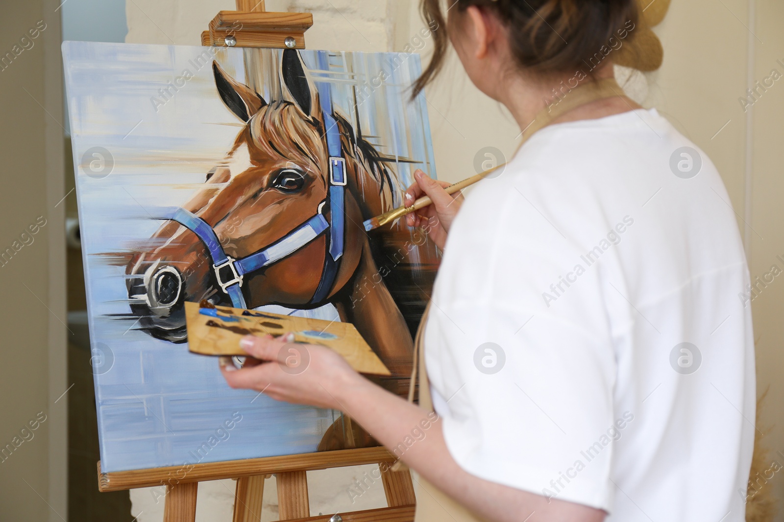 Photo of Woman drawing cute horse with brush in studio, closeup