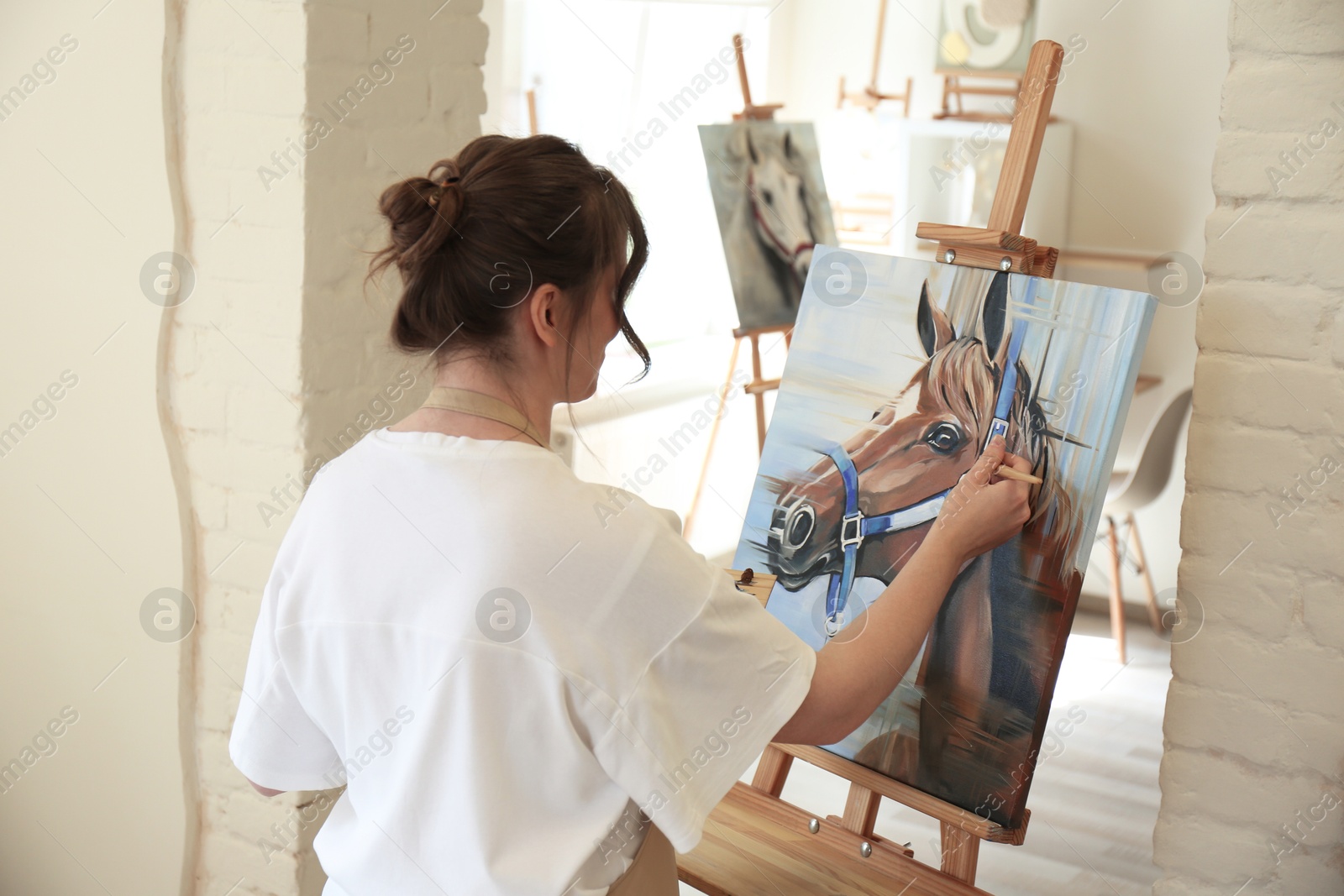 Photo of Woman drawing cute horse with brush in studio