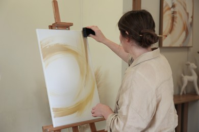 Woman creating picture with sponge in drawing studio