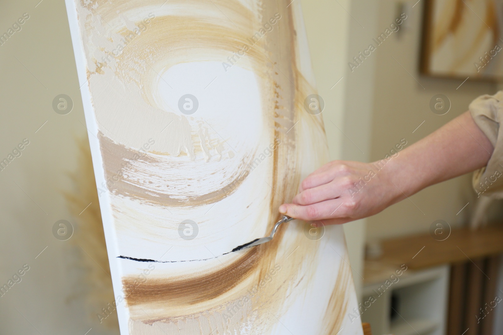 Photo of Woman with palette knife drawing picture in studio, closeup