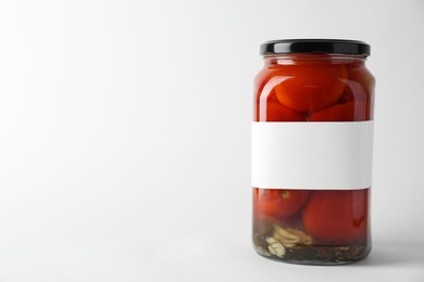 Photo of Tasty pickled tomatoes in jar on light background. Space for text