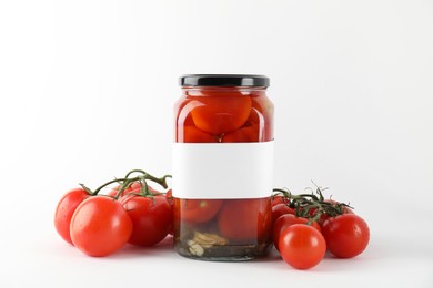 Tasty pickled tomatoes in jar and vegetables on light background