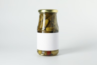 Pickled cucumbers in jar on light background