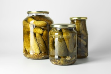 Pickled cucumbers in jars on light background