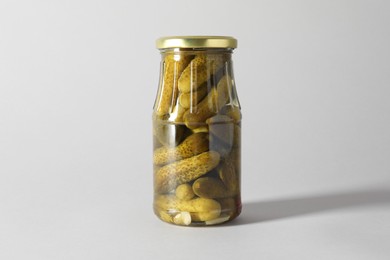 Photo of Pickled cucumbers in jar on light background