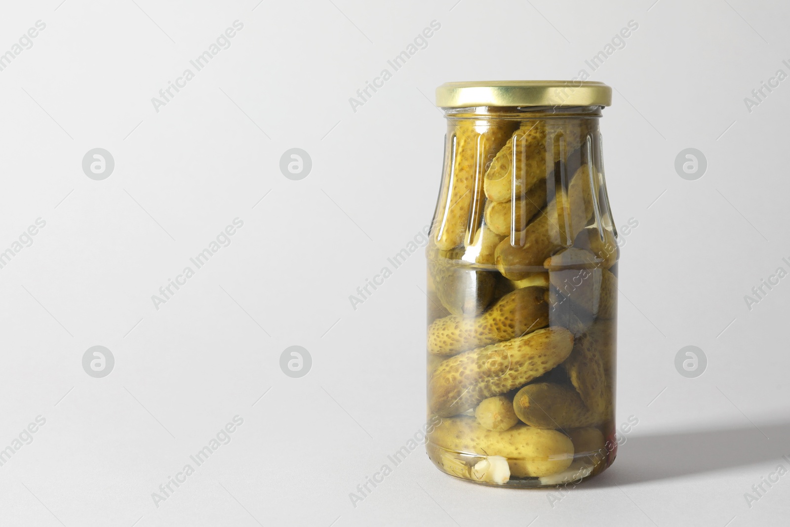 Photo of Pickled cucumbers in jar on light background. Space for text