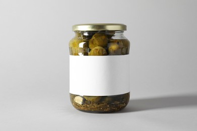 Pickled cucumbers in jar on light background