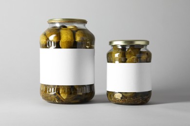 Pickled cucumbers in jars on light background