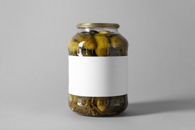 Pickled cucumbers in jar on light background