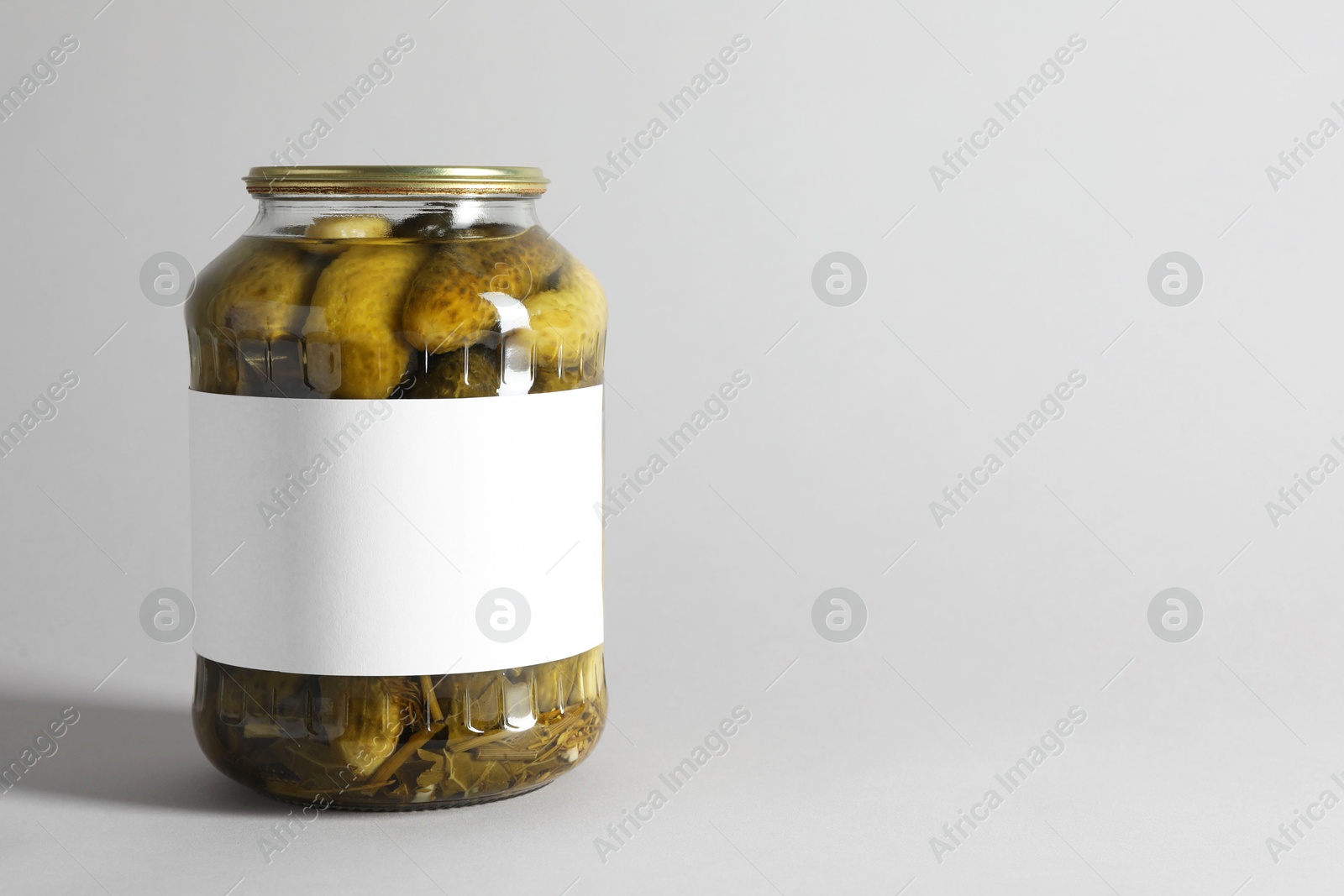 Photo of Pickled cucumbers in jar on light background. Space for text