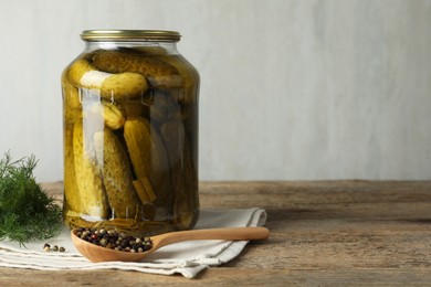 Pickled cucumbers in jar, dill and peppercorns on wooden table. Space for text