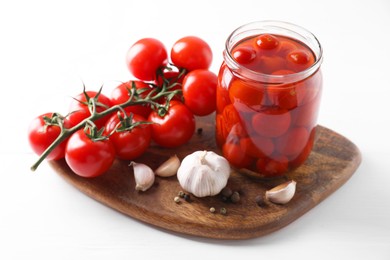 Tasty pickled tomatoes in jar, fresh vegetables and spices on white table