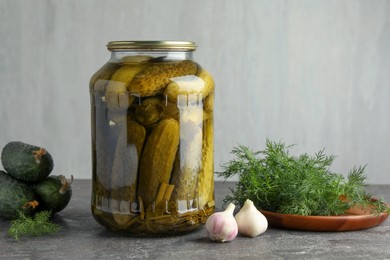 Photo of Pickles in jar, fresh cucumbers, dill and garlic on grey table