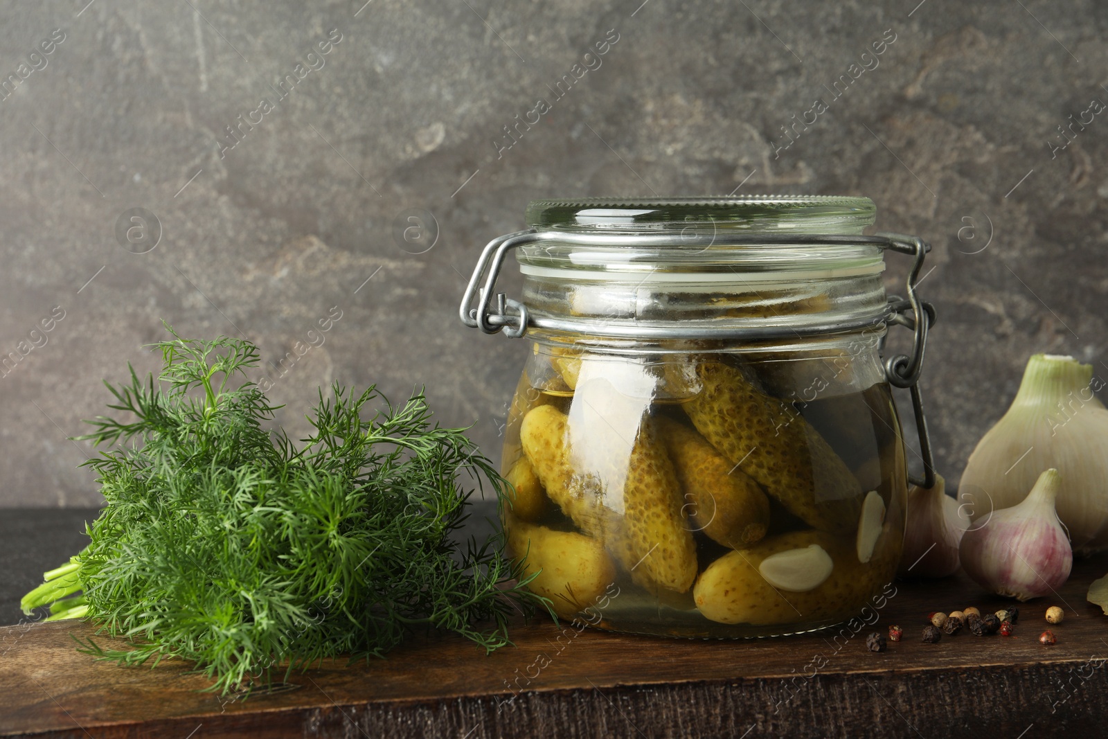 Photo of Pickled cucumbers in jar and spices on wooden table