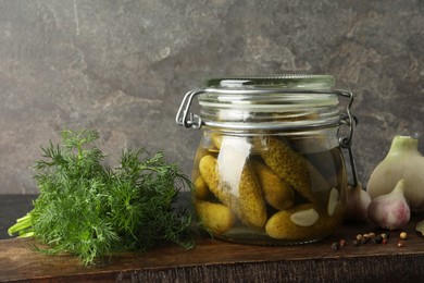 Photo of Pickled cucumbers in jar and spices on wooden table