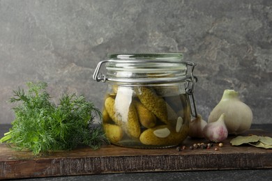 Photo of Pickled cucumbers in jar and spices on wooden table