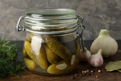 Photo of Pickled cucumbers in jar and spices on wooden table