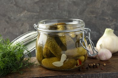 Photo of Pickled cucumbers in jar, dill and garlic on grey table