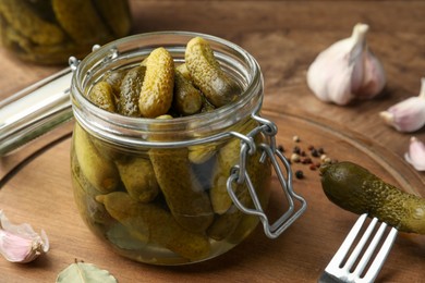 Photo of Pickled cucumbers in open jar on wooden table, closeup