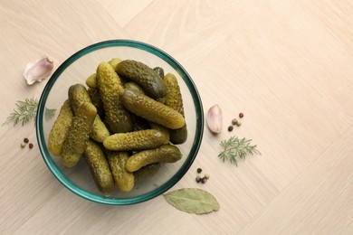 Photo of Pickled cucumbers in bowl and spices on light wooden table, flat lay. Space for text