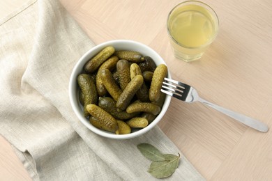 Photo of Pickled cucumbers in bowl, fork and brine on wooden table, flat lay